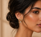 Close-up of a woman wearing a gold earring with a clear gemstone against a neutral background